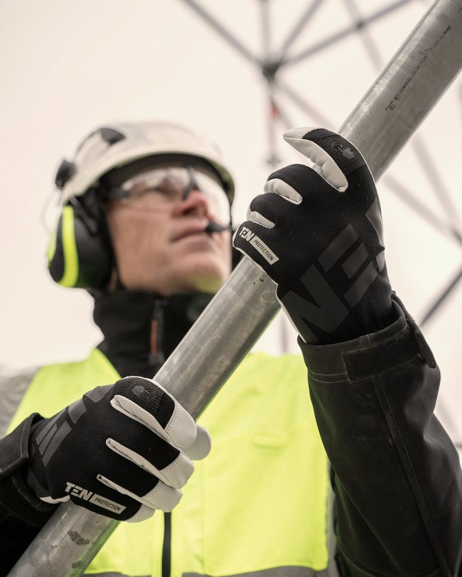 Trabajador con casco, protección auditiva, lentes y guantes manipula un tubo metálico